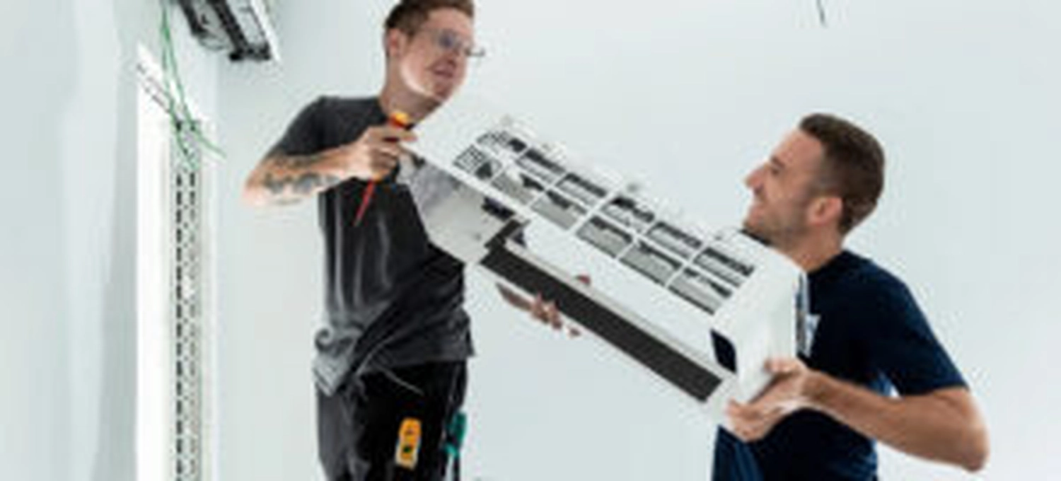 Elektro Wollmer GmbH - Innovative Klimatechnik - Zwei Arbeiter reparieren eine Klimaanlage.
